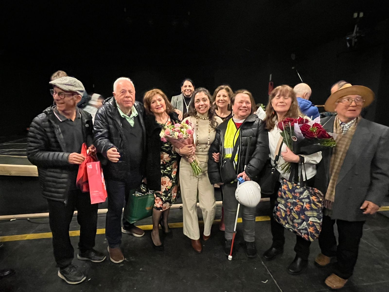 Participantes posando con ramos de flores tras la función de cierre