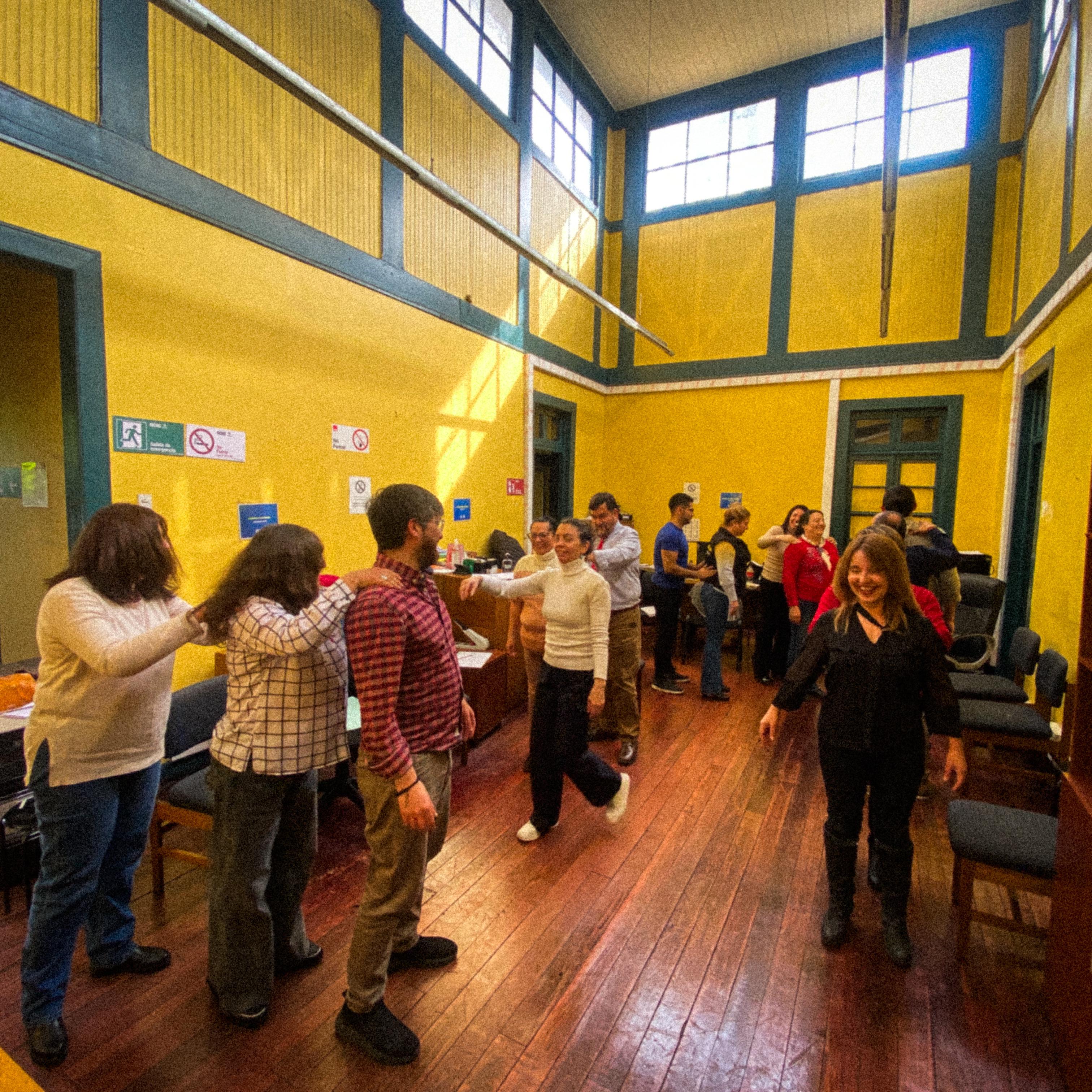 Participantes trabajando en duplas durante un ejercicio corporal en una sala de muros amarillos